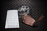 Golf club head cover with a sheet of golf ball markers on a textured black surface.