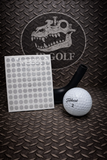 Golf ball, sheet of stickers, and black tee on a textured metal surface with a logo in the background.