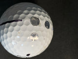 a white golf ball with an example of the OEM metal dot, the thin metal dot, and our OEM thick metal dot. 