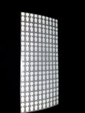 a sheet of tabbed foresight dots on a black background under a light. 